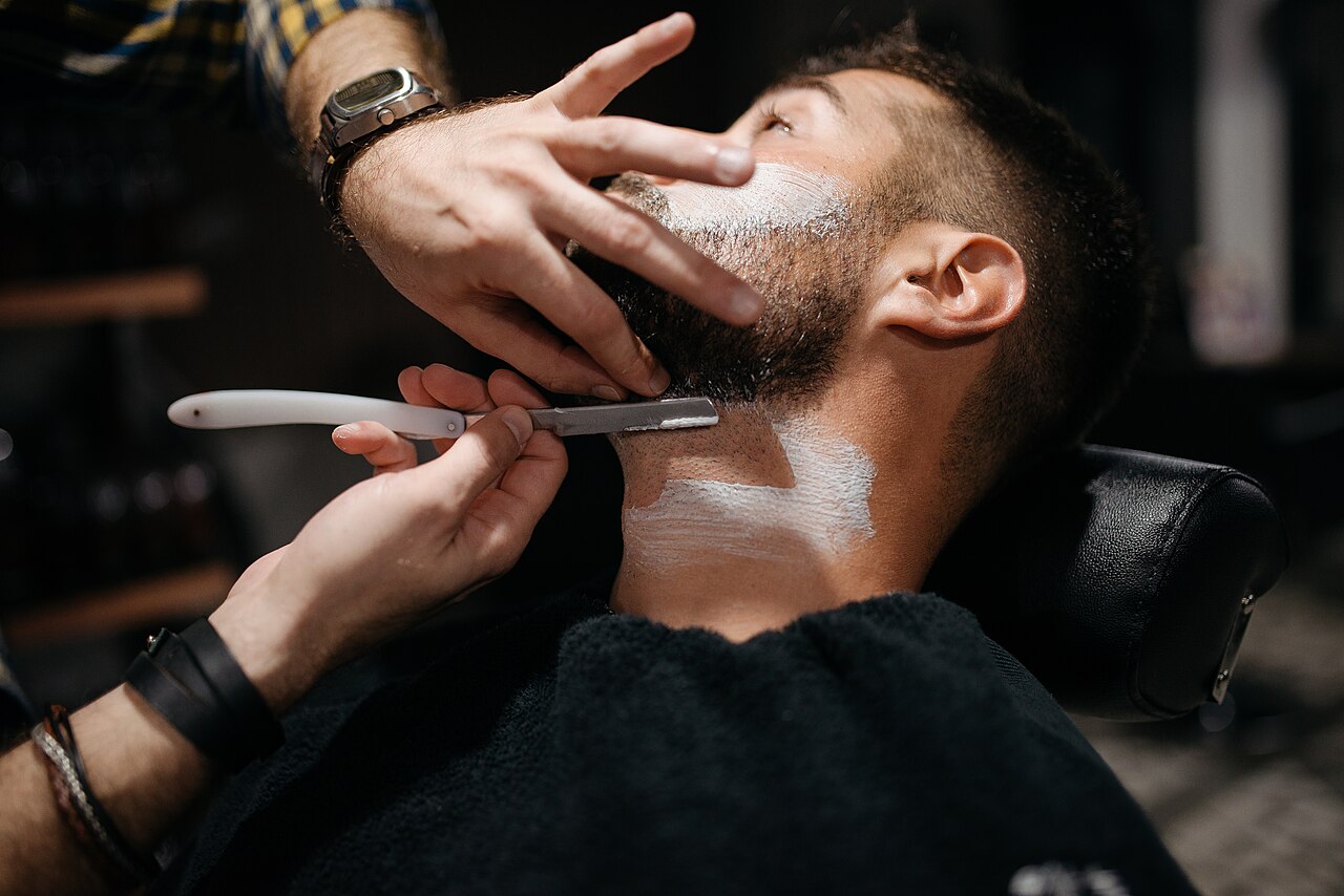 Un barbier rase la barbe d'un client au coupe-chou
